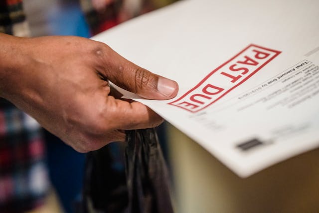 Person holding a paper that says in red lettering "past due"
